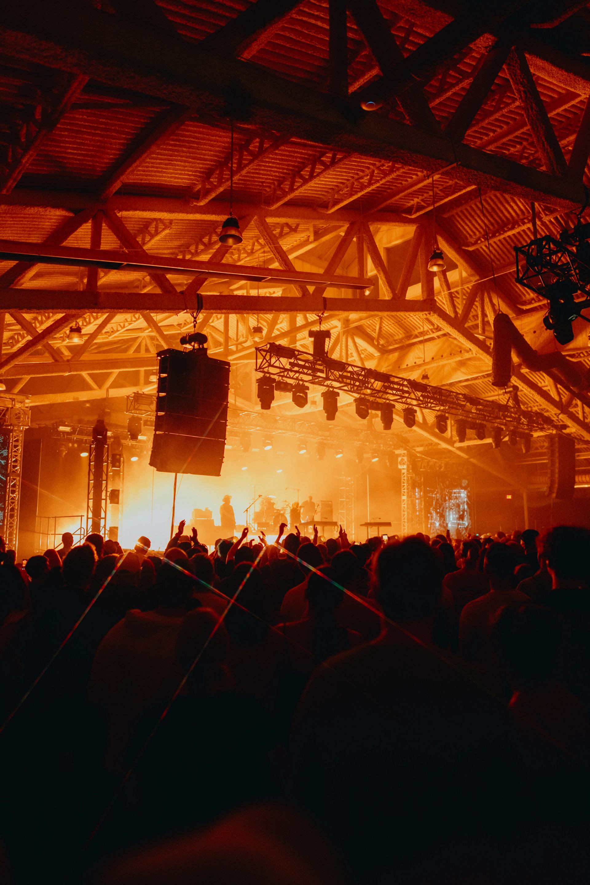 Crowd watches musicians perform on a brightly lit indoor stage.