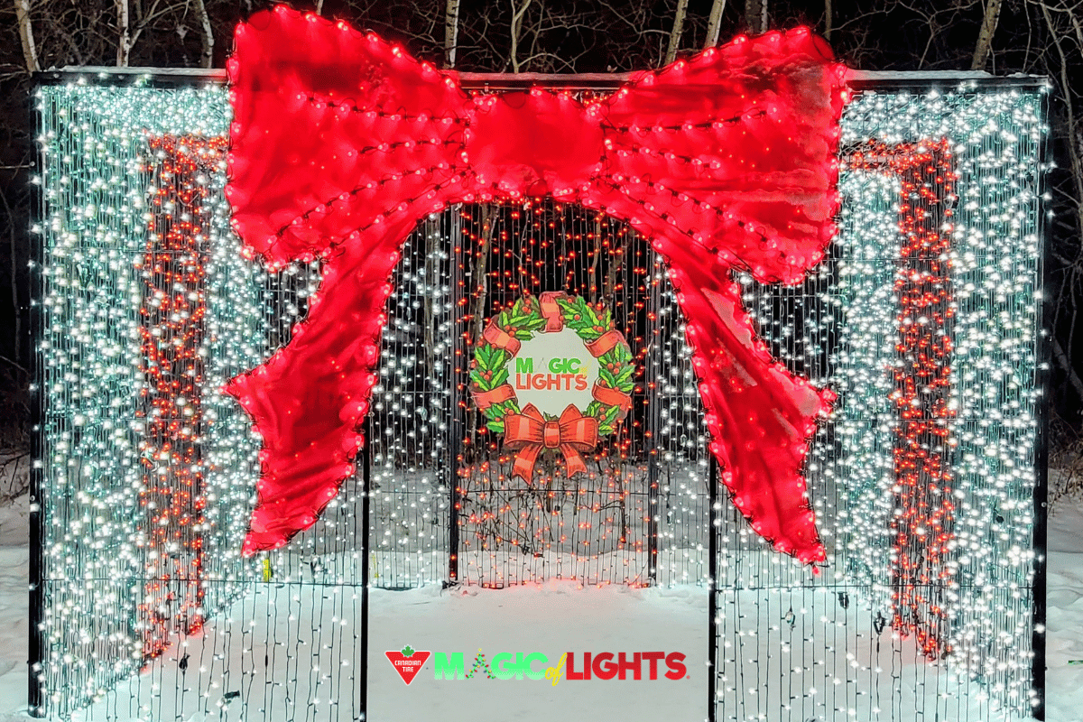 Large red bow and wreath made of holiday lights at Magic of Lights display.