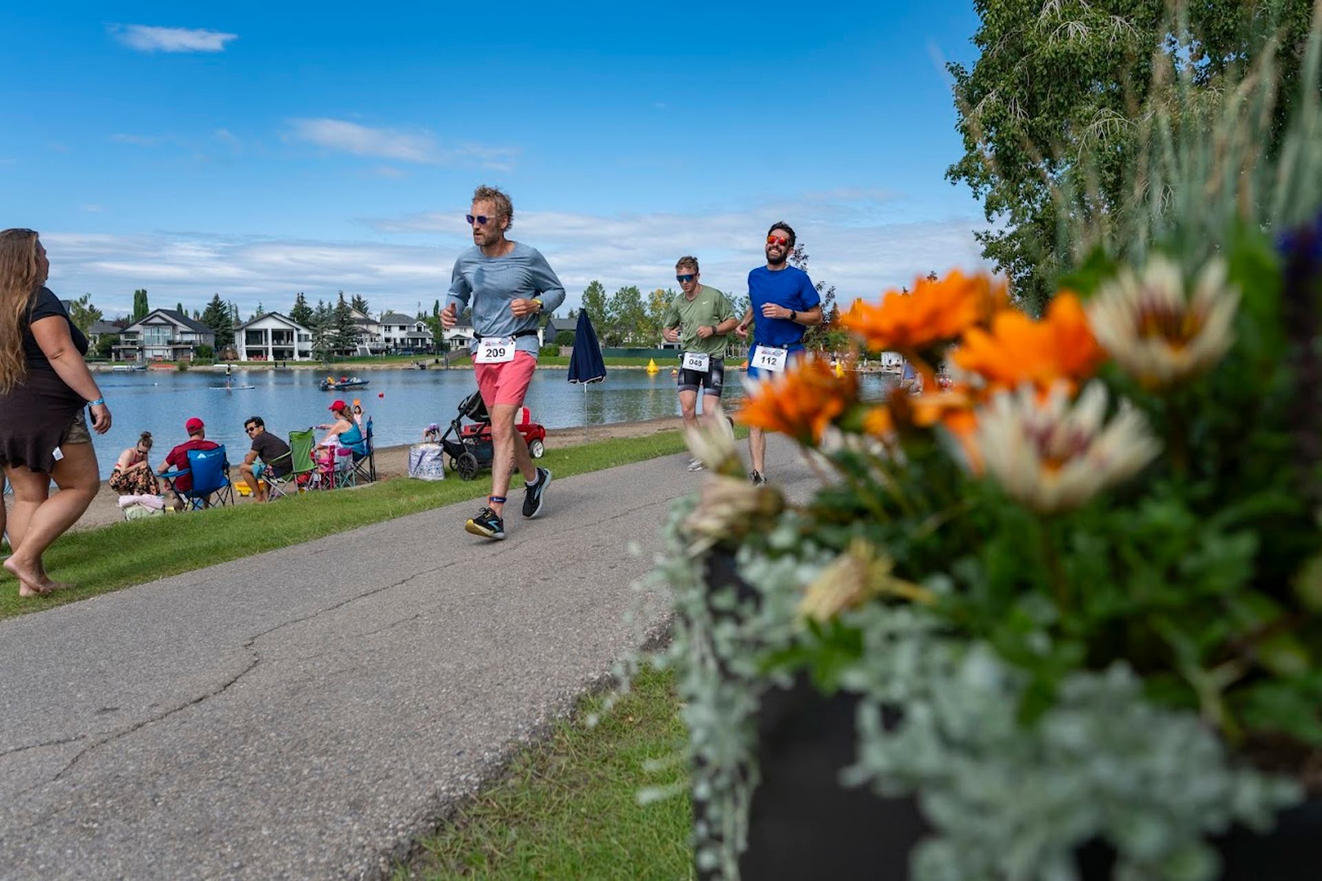 Athletes running along a lakeside path during the Lake Chaparral Triathlon.