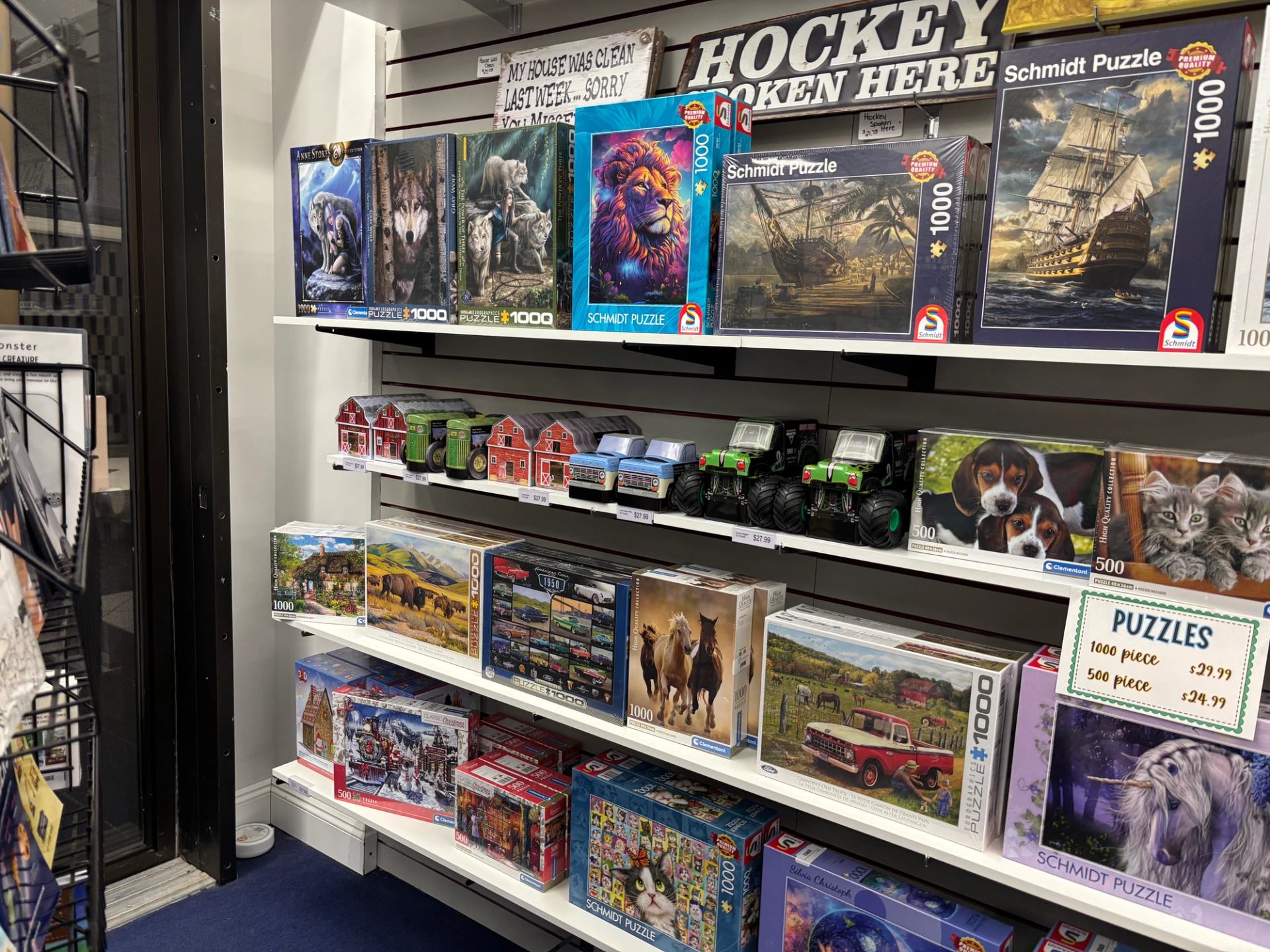 Store shelves filled with jigsaw puzzles, games, and toy vehicles, neatly arranged in a children’s gift shop.