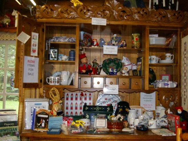 Wooden cabinet with mugs, books, and collectibles for sale at Norwegian Laft Hus.
