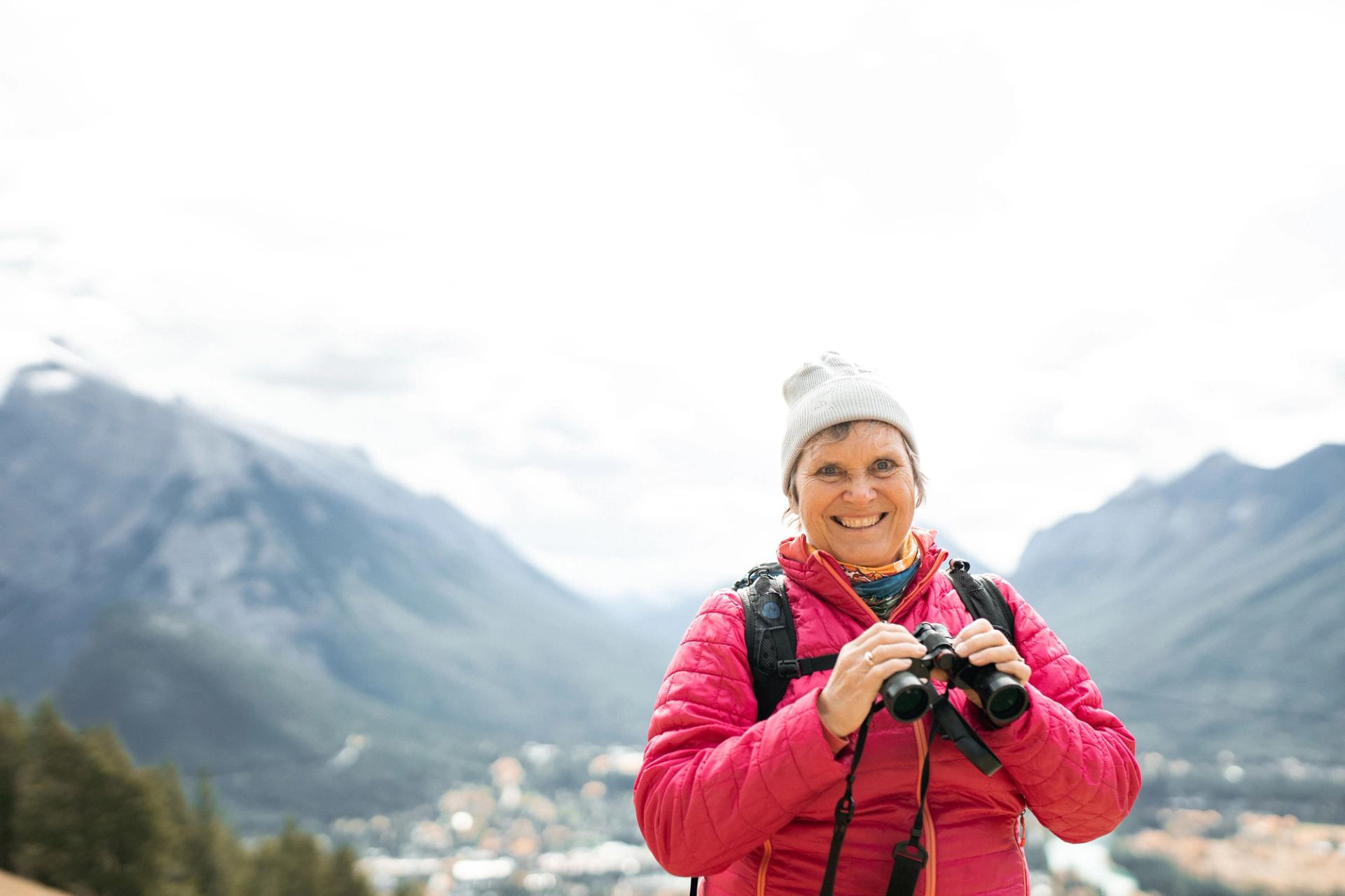 Woman in pink jacket holding binoculars in the mountains near Banff, Alberta