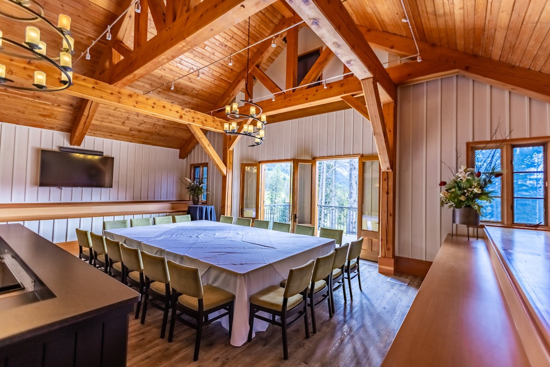 Boardroom with high wooden beams and large windows looking out to the forest