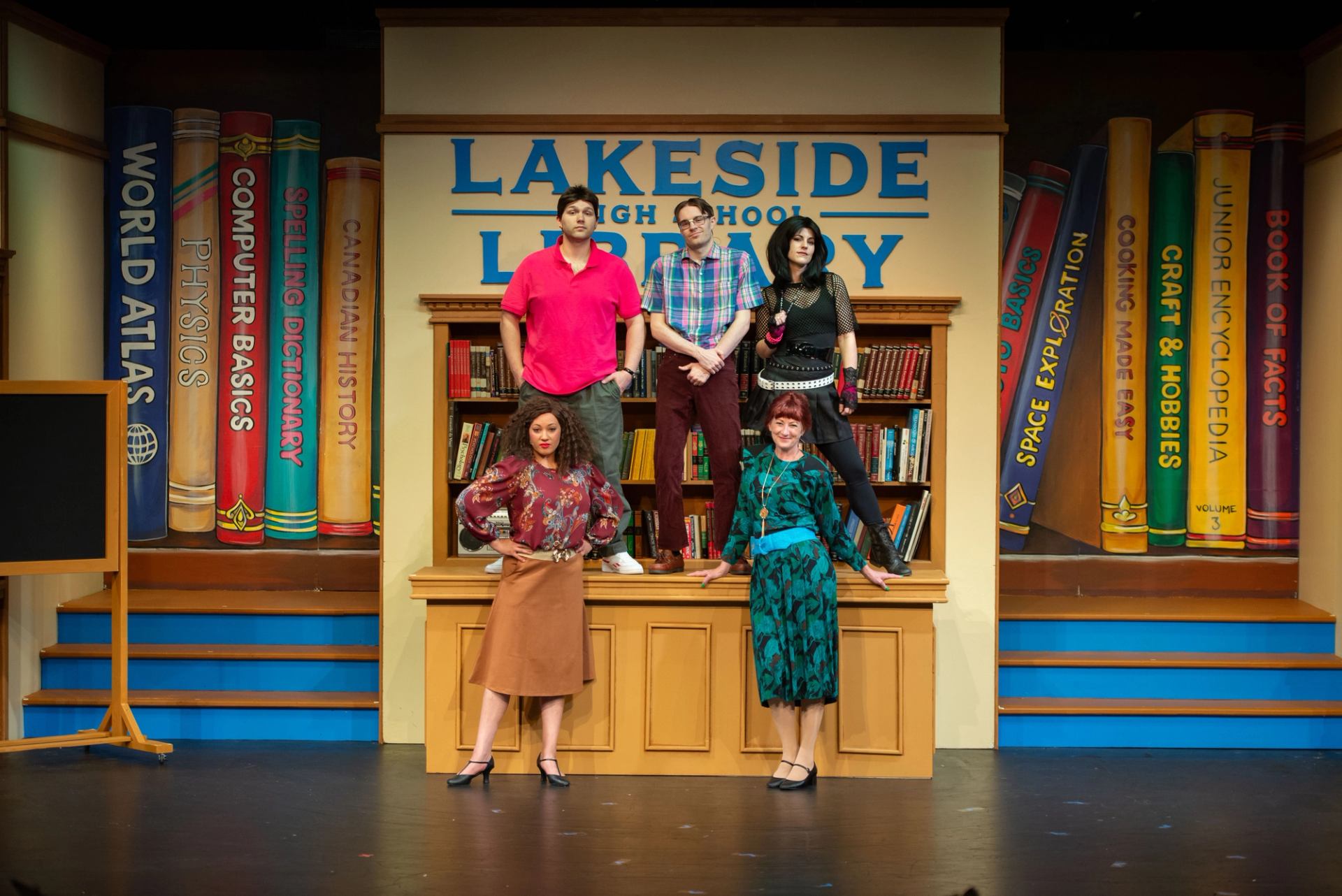 The 5 - member cast of Back to the '80s: The Magic Mixtape standing on and around a counter top