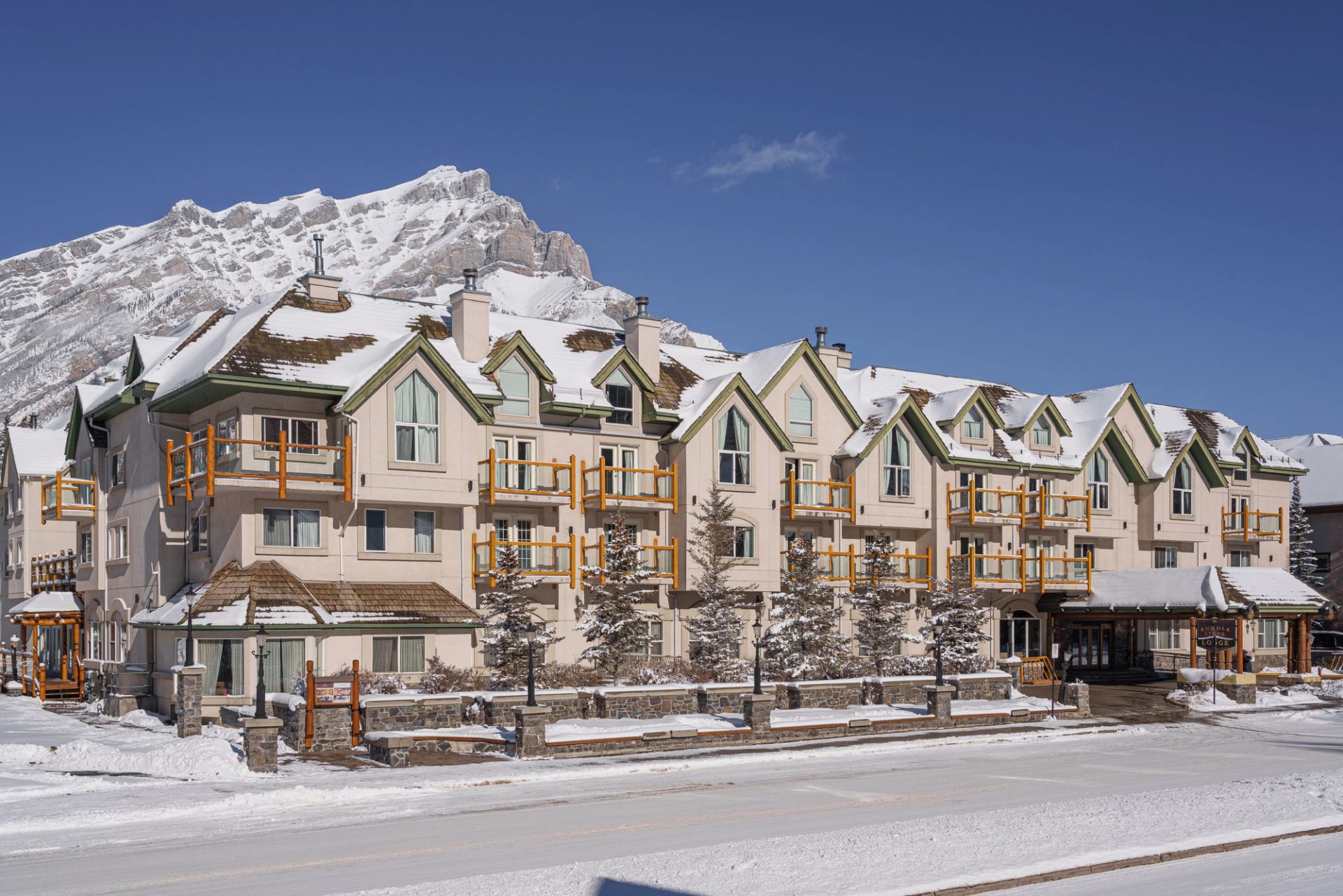 Snow-covered Rundlestone Lodge with mountain views and blue sky.