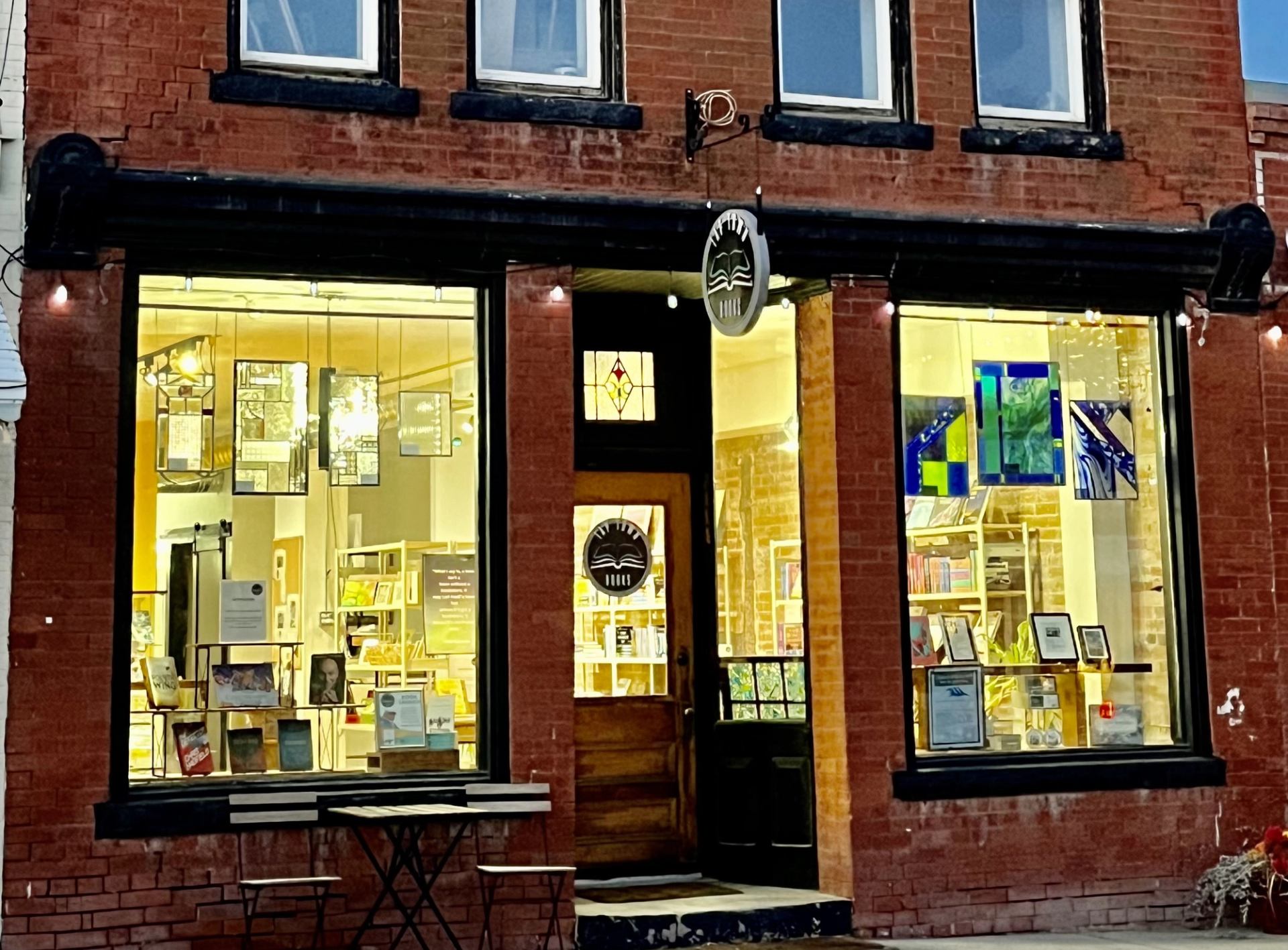 Brick storefront with open doorway and large windows showing books and artwork, Tap Town Books.