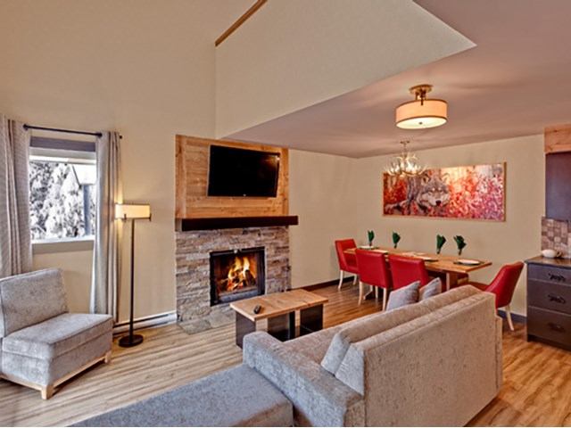 Open-concept lodge suite with fireplace, sofas, and dining area.