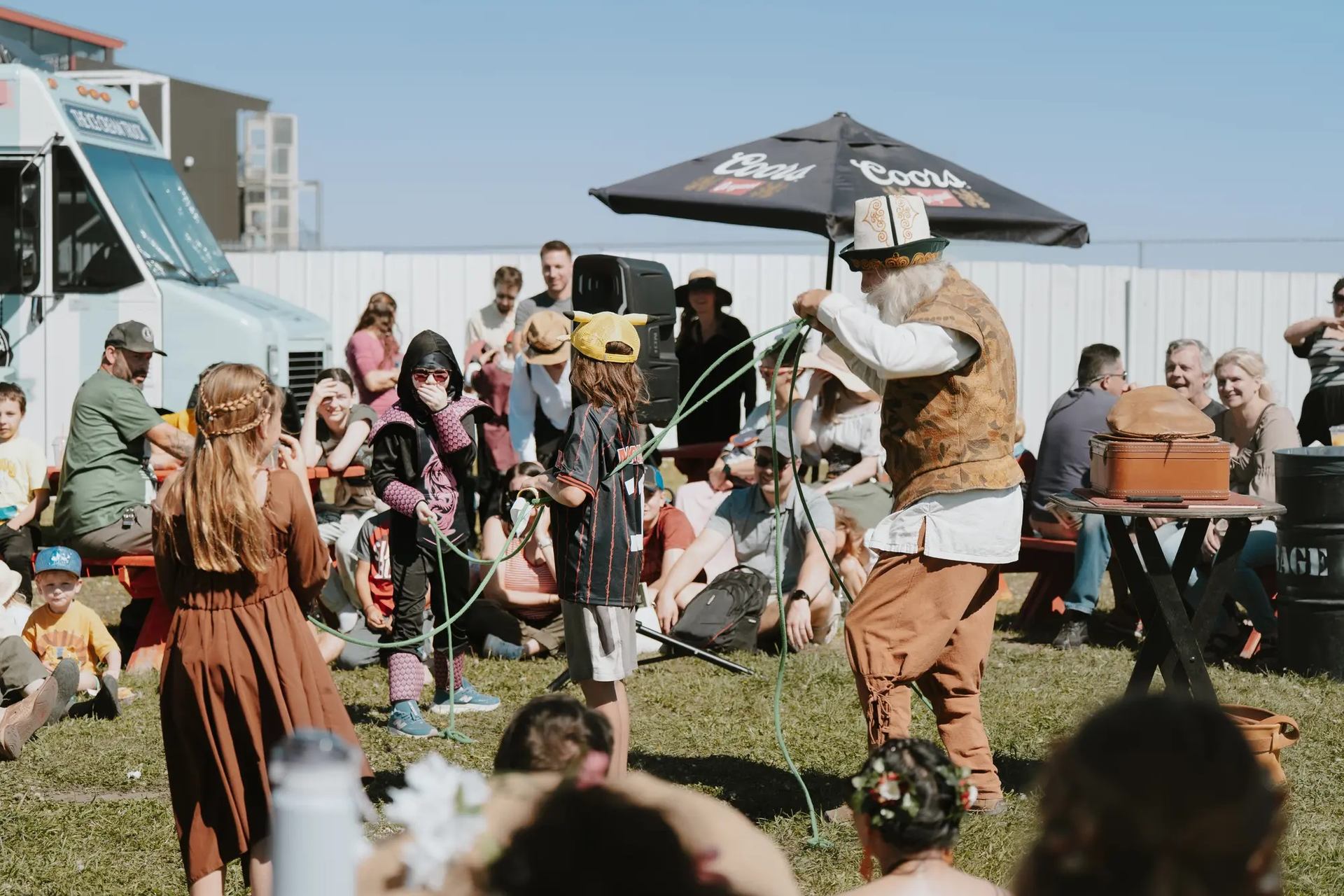 Performer entertains crowd with ropes at Vegreville Medieval Faire near food truck.