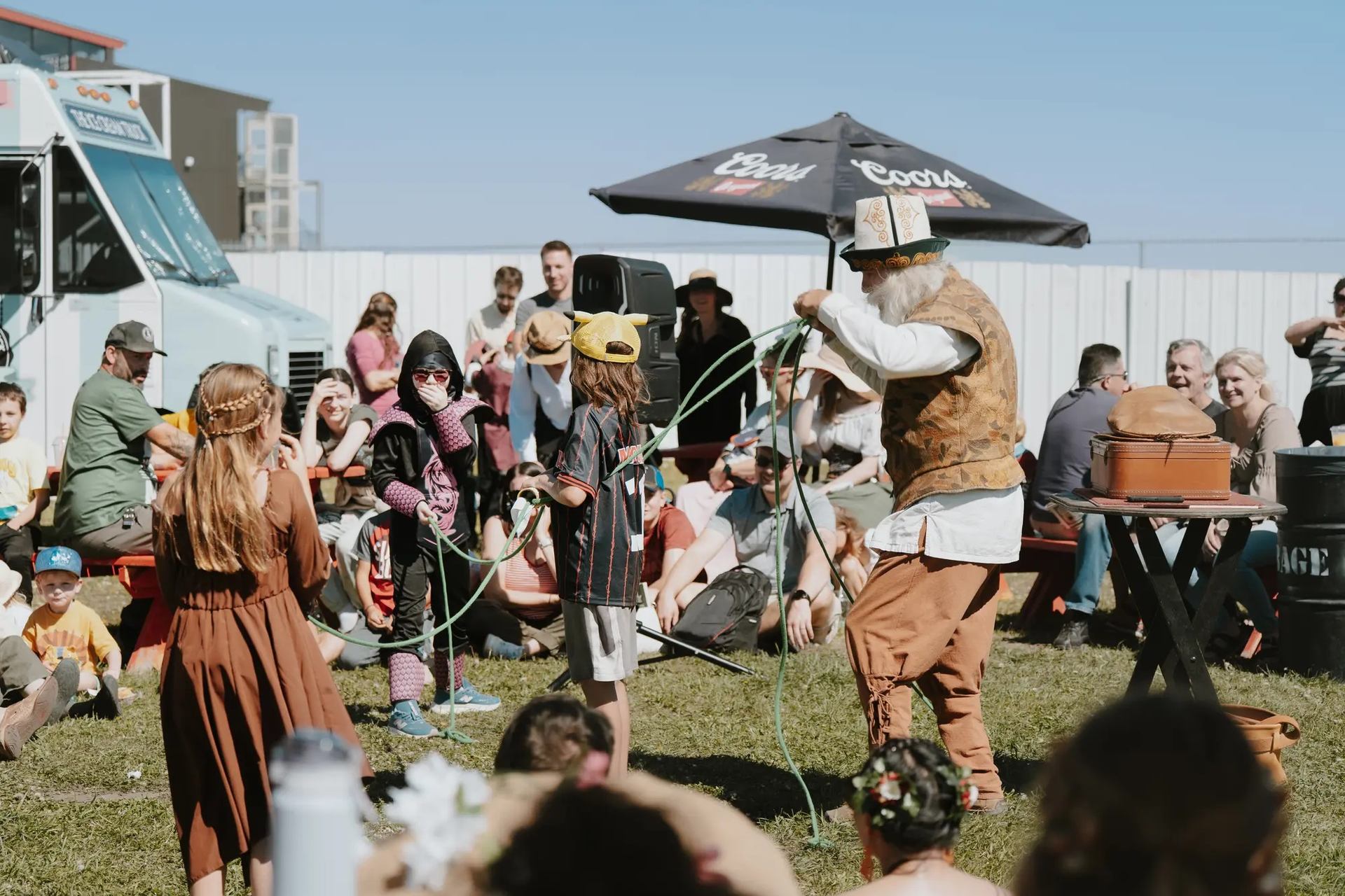 Performer entertains crowd with ropes at Vegreville Medieval Faire near food truck.