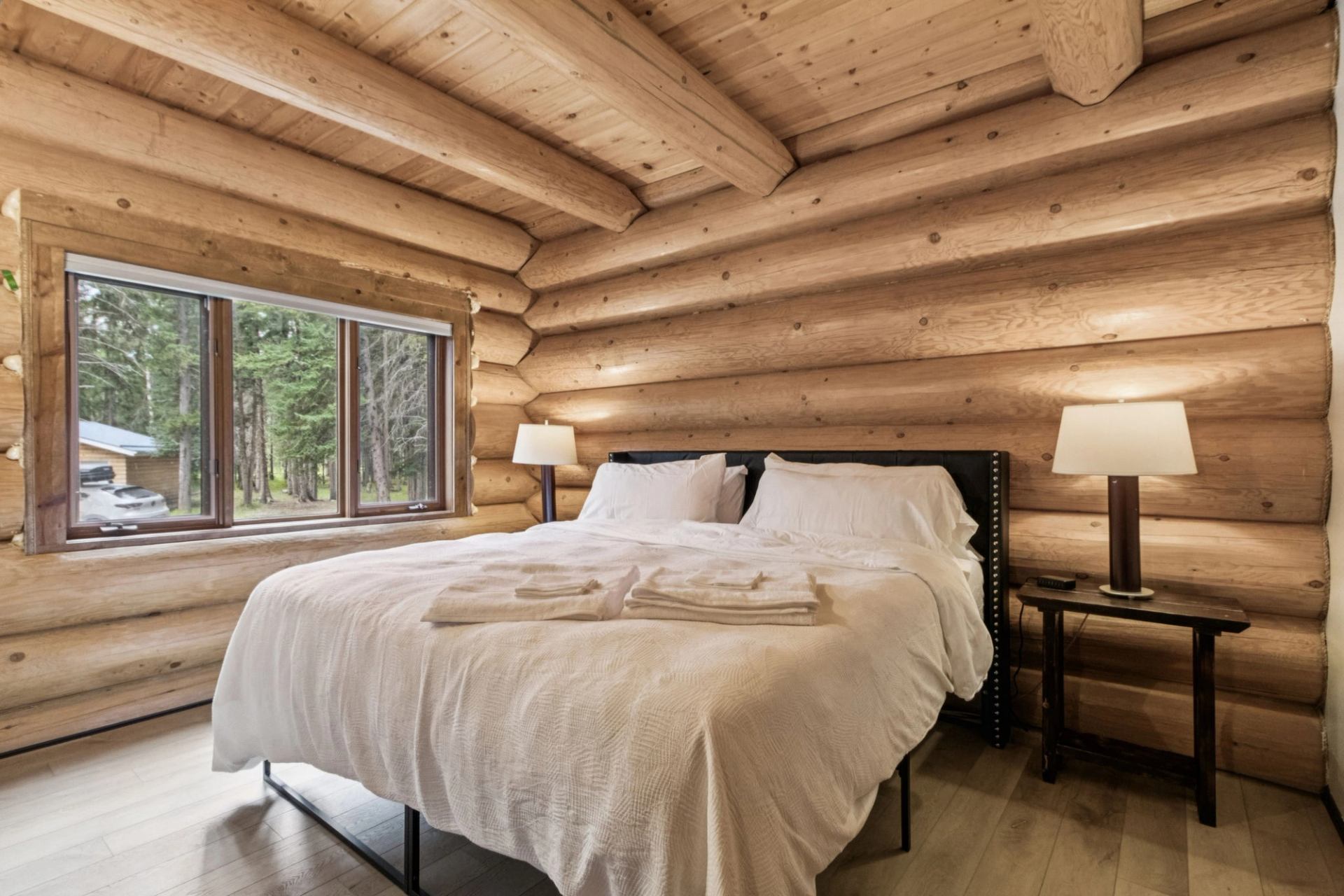 Rustic log cabin bedroom with white linens and natural light.