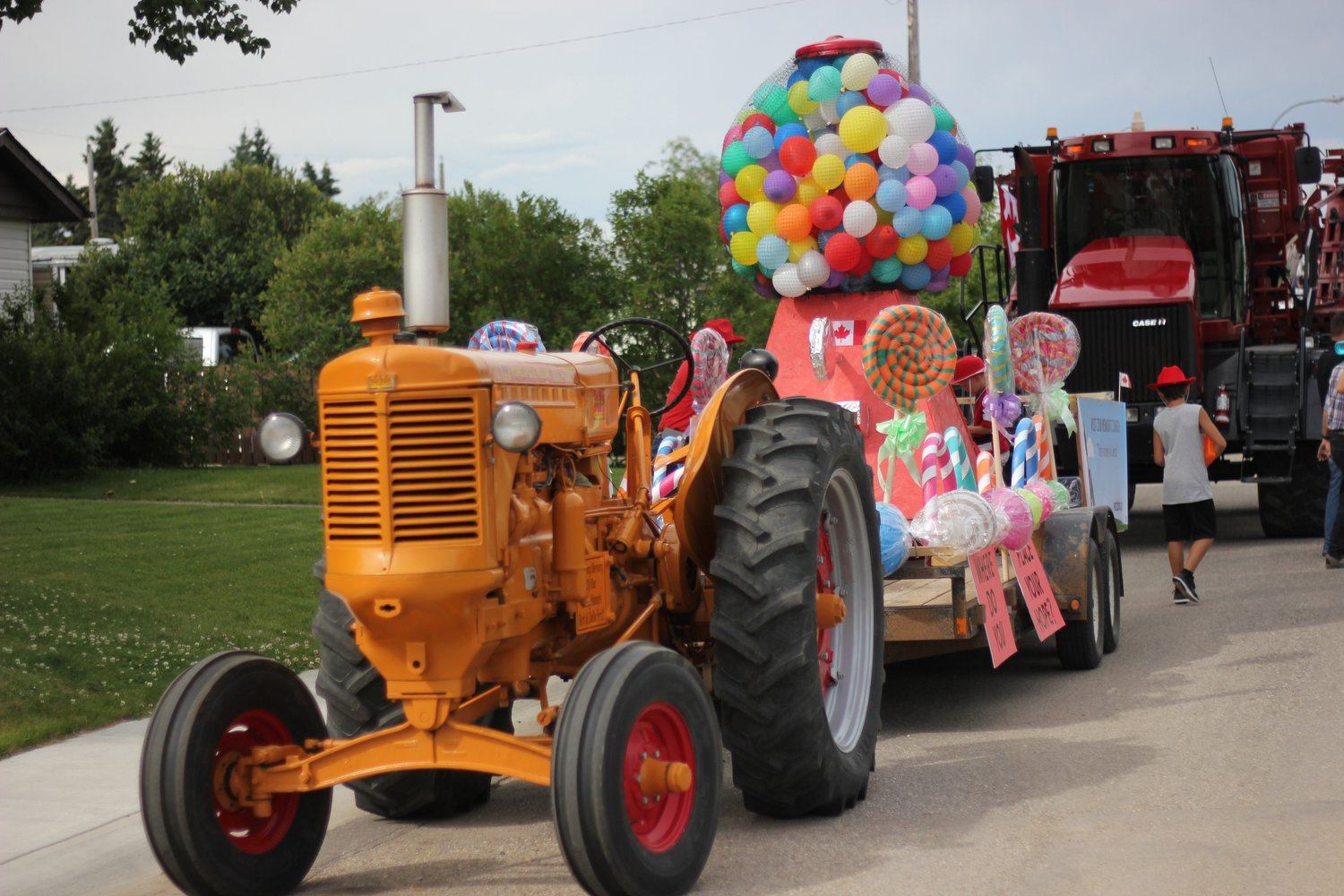 The parade with floats, a tractor with balloons leading the parade.