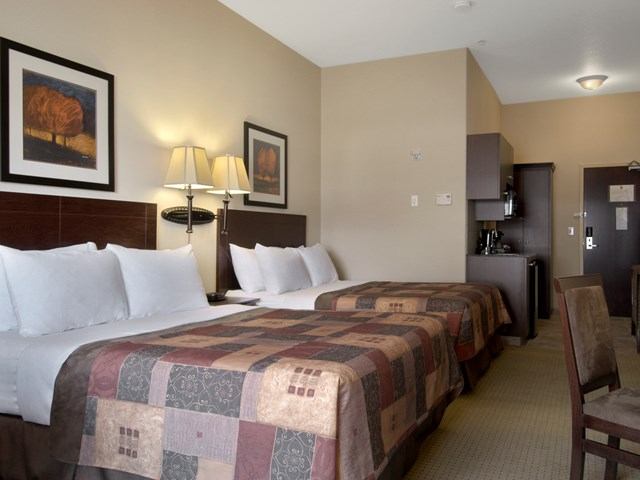 Hotel room with two beds, kitchenette, and autumn-themed decor.