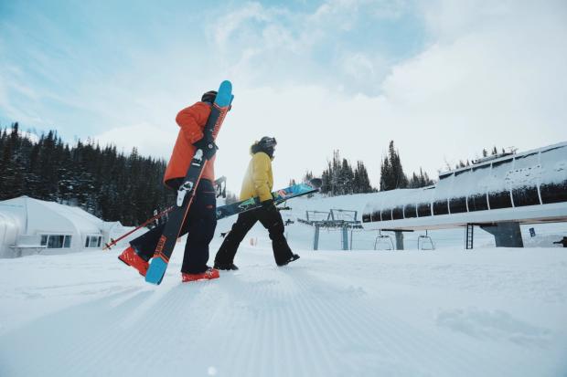 Two people carrying their gear before skiing at Sunshine Village.