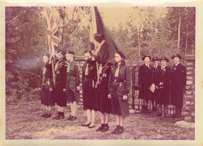 A historical photograph shows Guiding members holding flags during a ceremonial gathering.