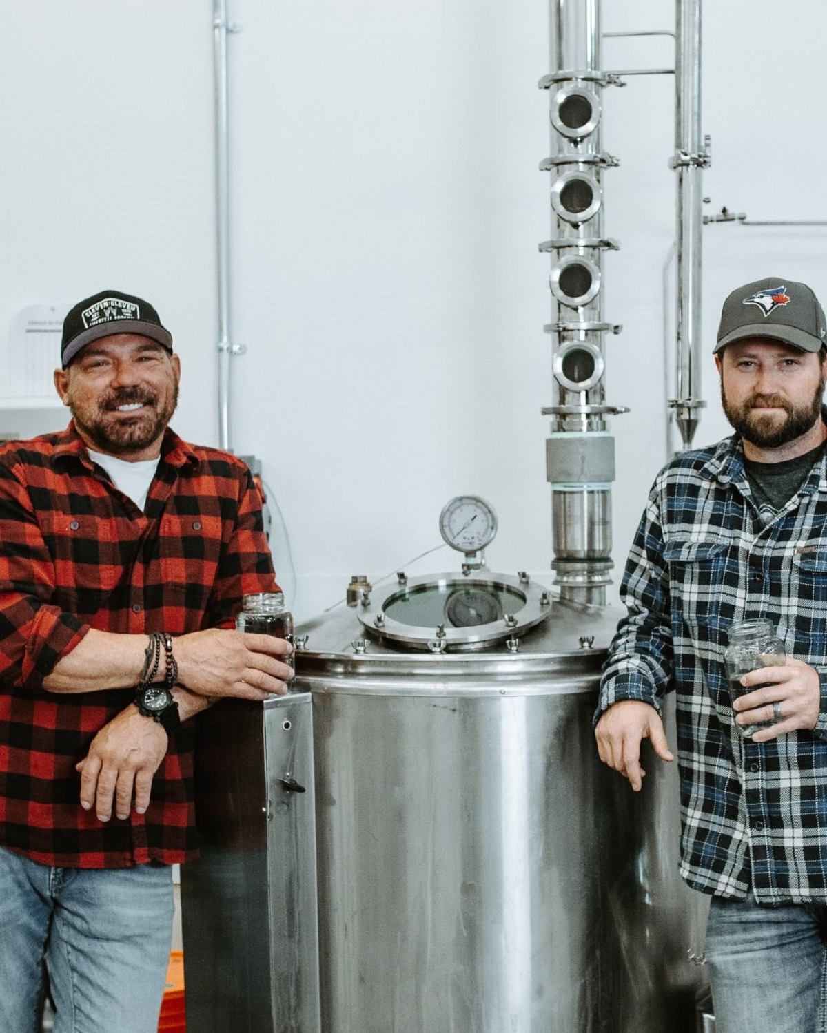 The Booze Brothers holding a drink in the distillery.