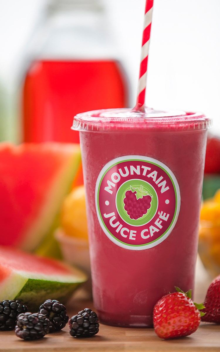 Pink smoothie with striped straw and assorted fruits around cup labeled Mountain Juice Café.