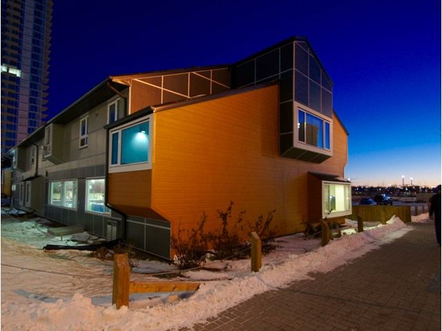 Modern hostel building with angular design, glowing windows, and snowy urban surroundings.
