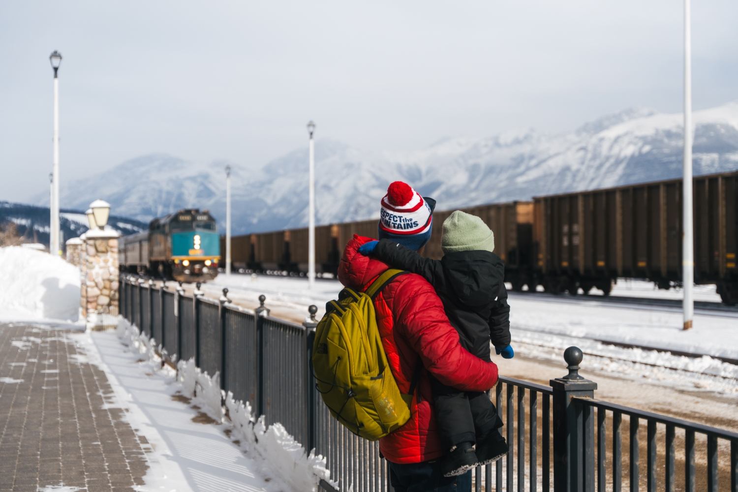 A man with a child in their arms watching the train arrive.