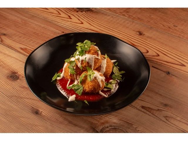 Fried arancini balls on tomato sauce, drizzled with white sauce and fresh herbs.