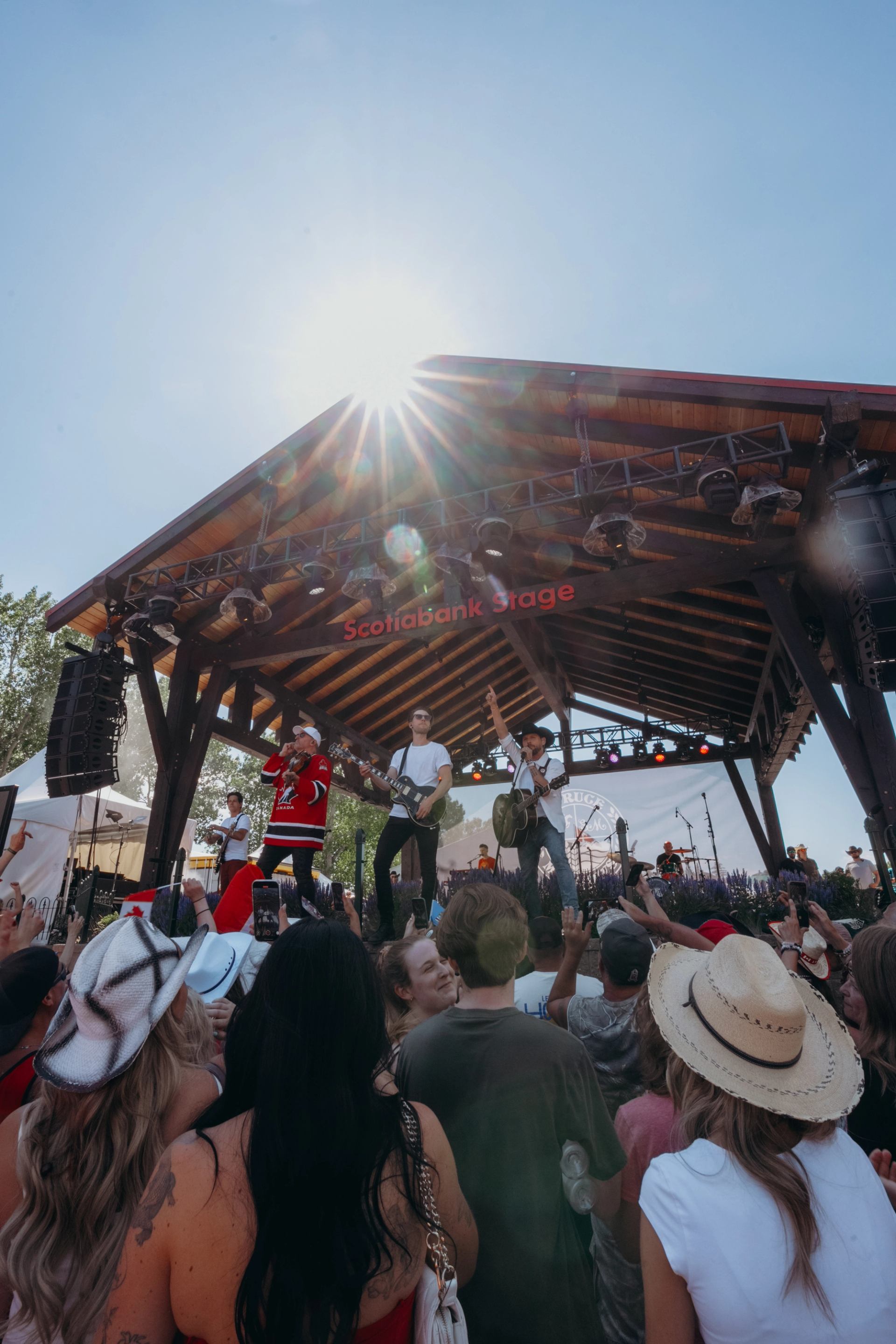 Band performing on an outdoor stage with a cheering audience