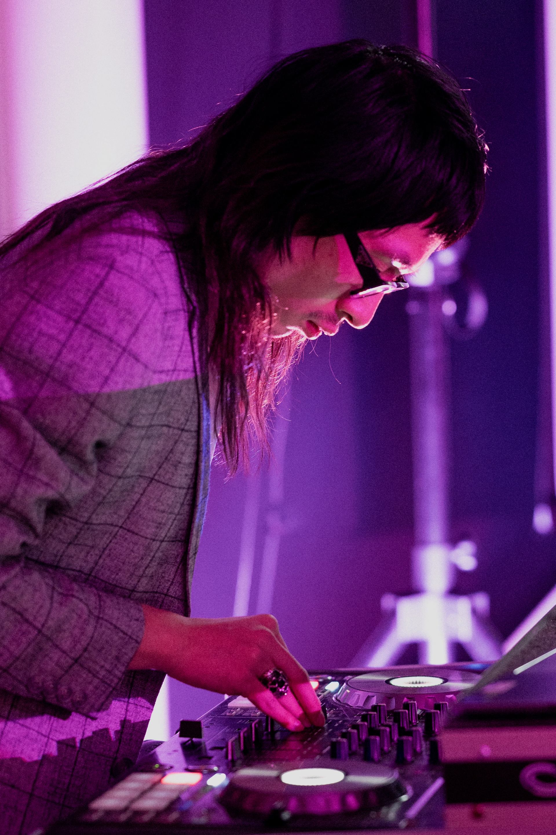 Person hovering over DJ gear in pink light