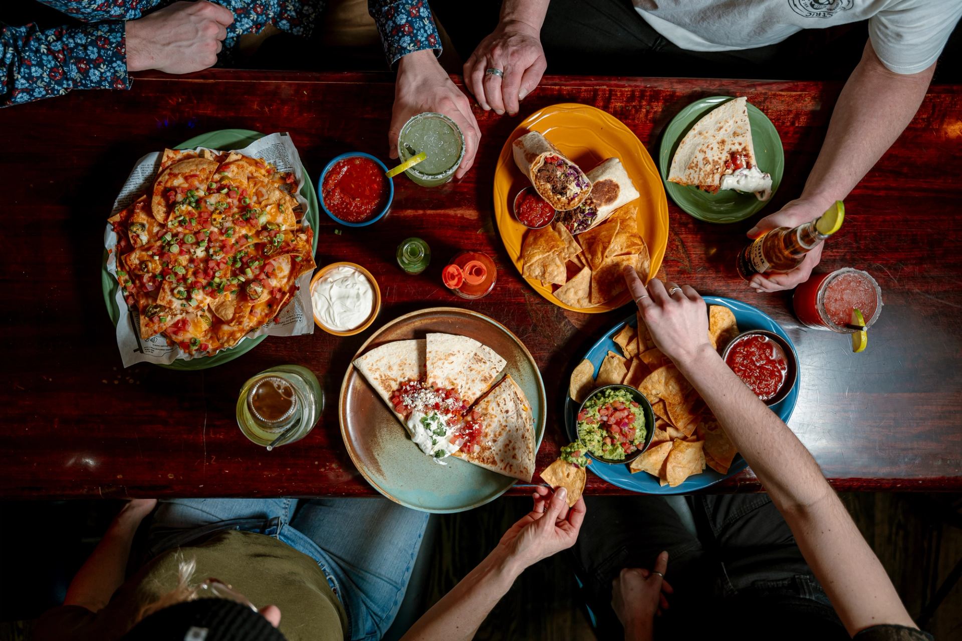 Colourful plates of nachos, quesadillas, burritos, and guacamole and chips