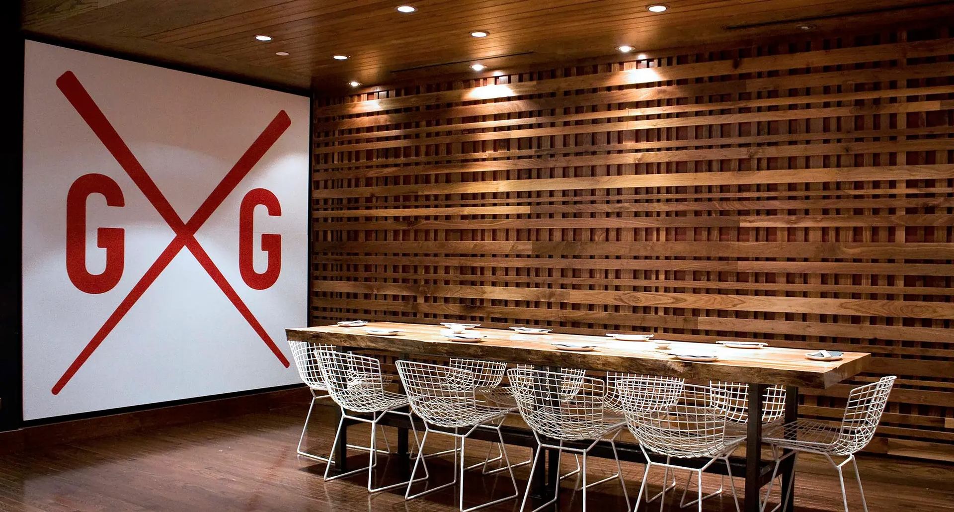 Stylish dining area with wooden table, wire chairs, and Goro + Gun wall art.