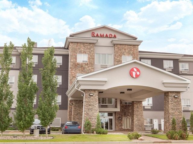 Exterior view of Ramada Camrose Hotel & Suites with stone façade and entrance canopy.