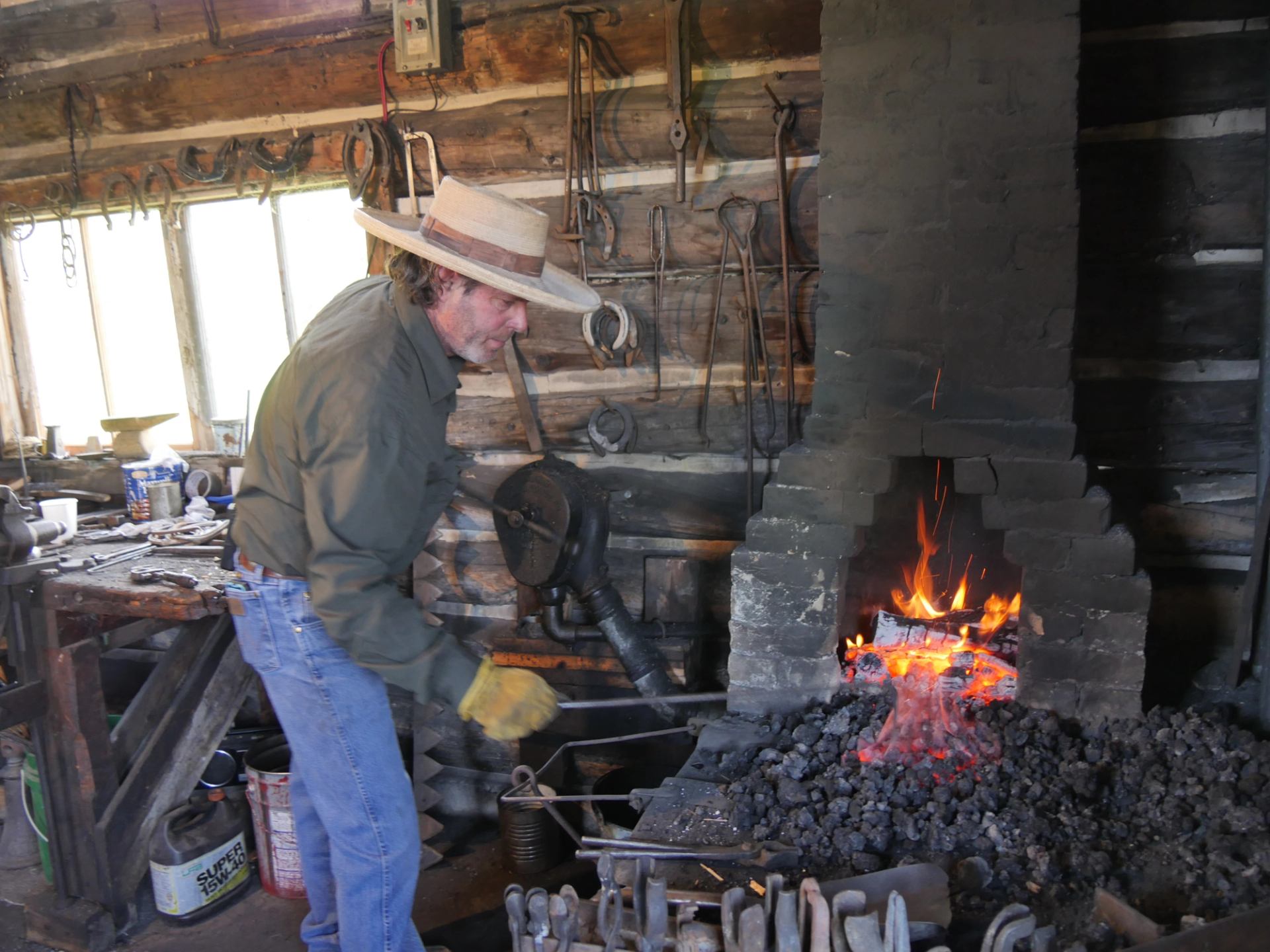 A blacksmith works at a glowing forge inside a rustic workshop at Bar U Ranch.