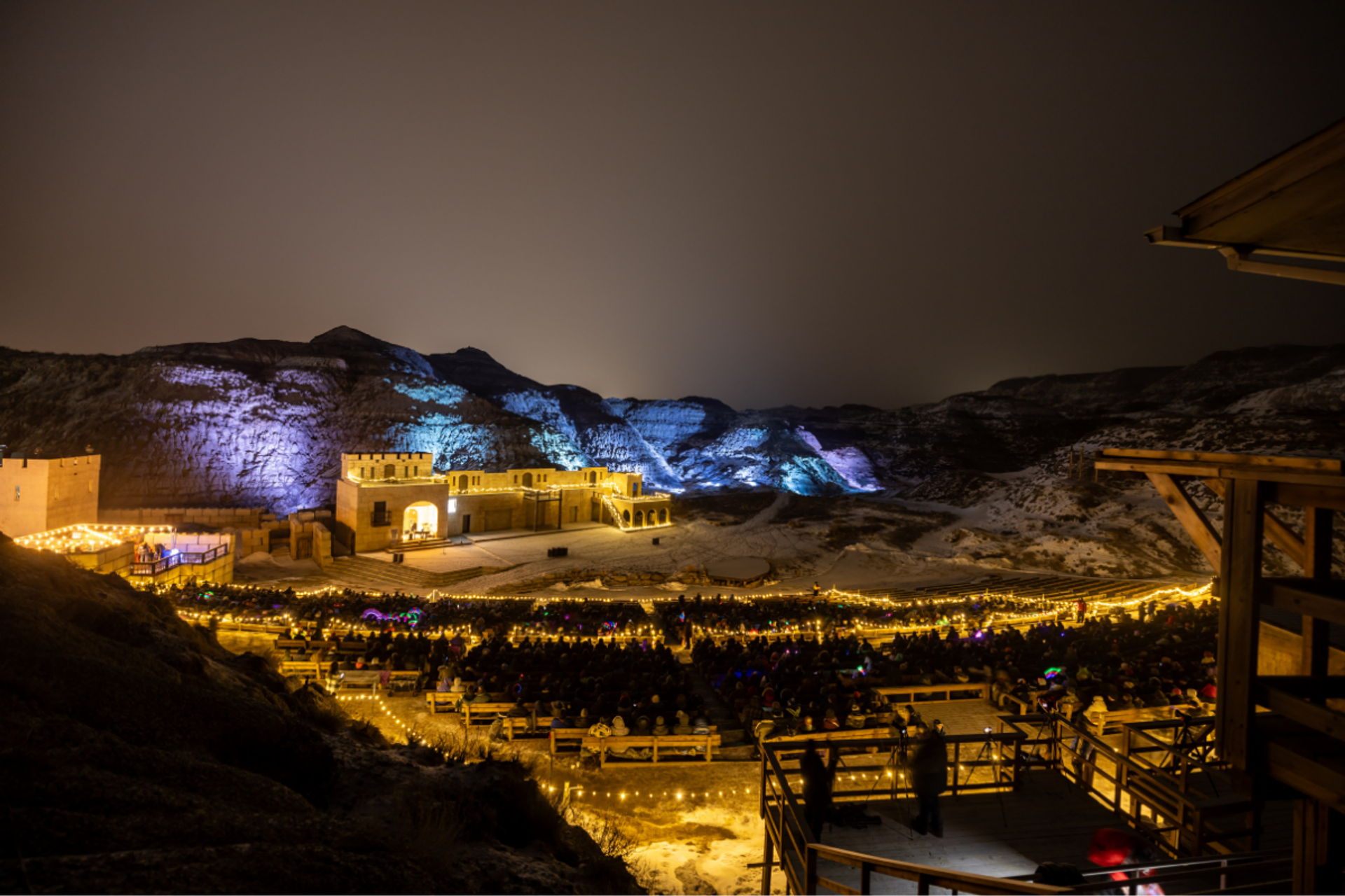 The Badlands Amphitheatre at night with blue and purple lights on the hills.
