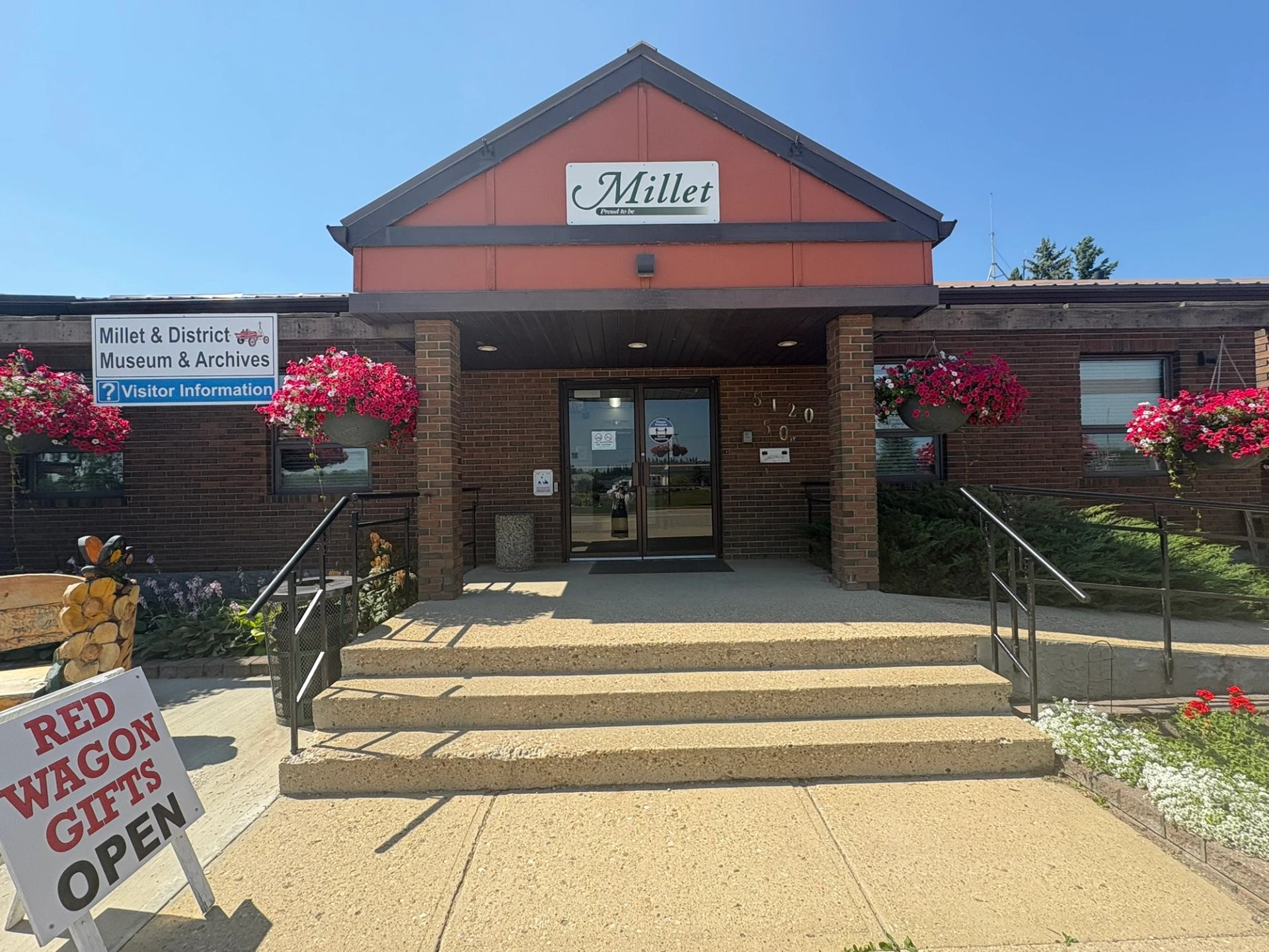Front entrance of Millet and District Museum with flower baskets and signage.