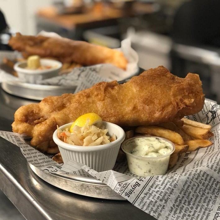 Plate of golden fried fish with fries, coleslaw, and tartar sauce at Waters Edge Pub & Café.
