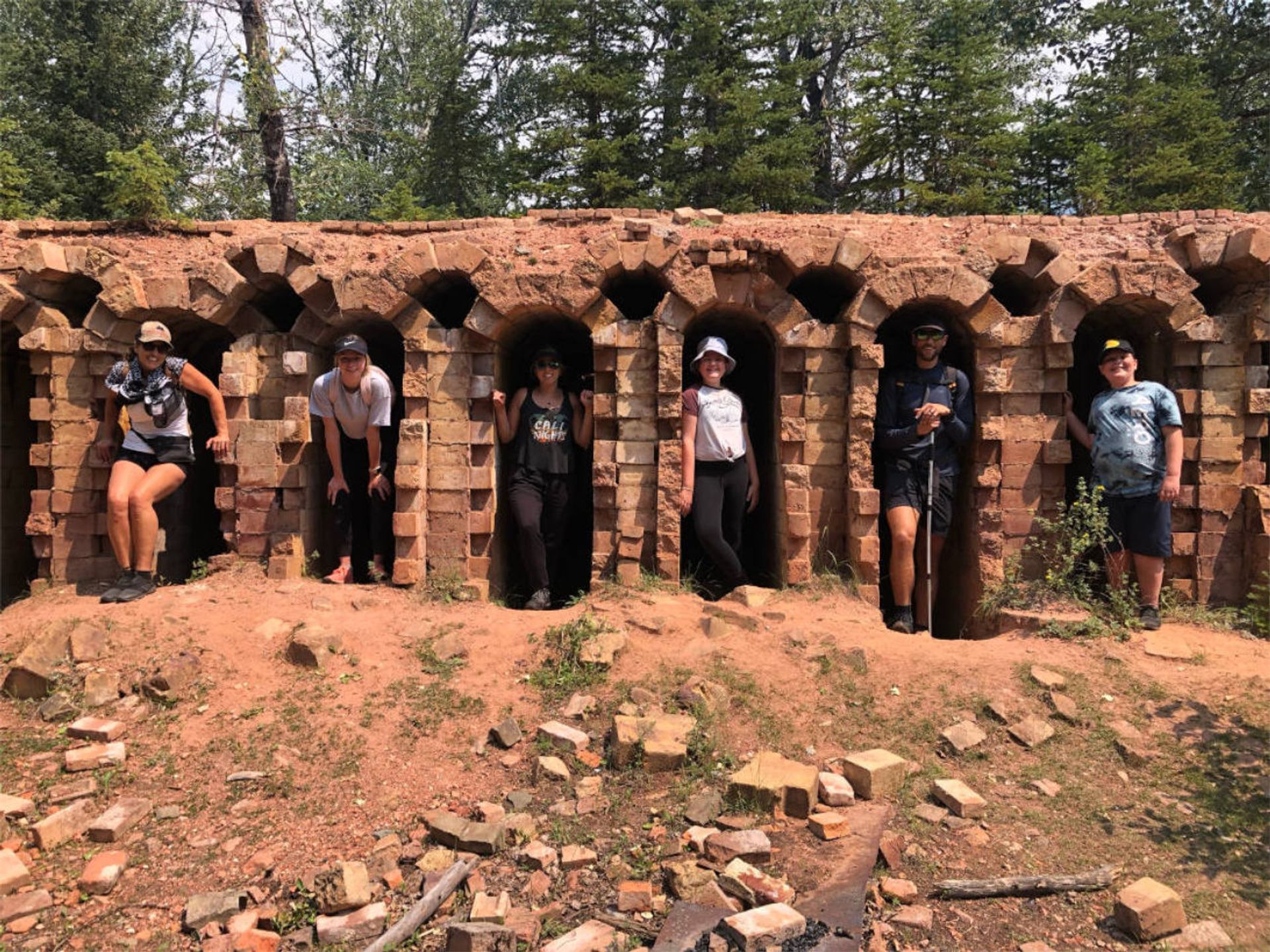Hikers standing in arched brick ruins surrounded by trees.