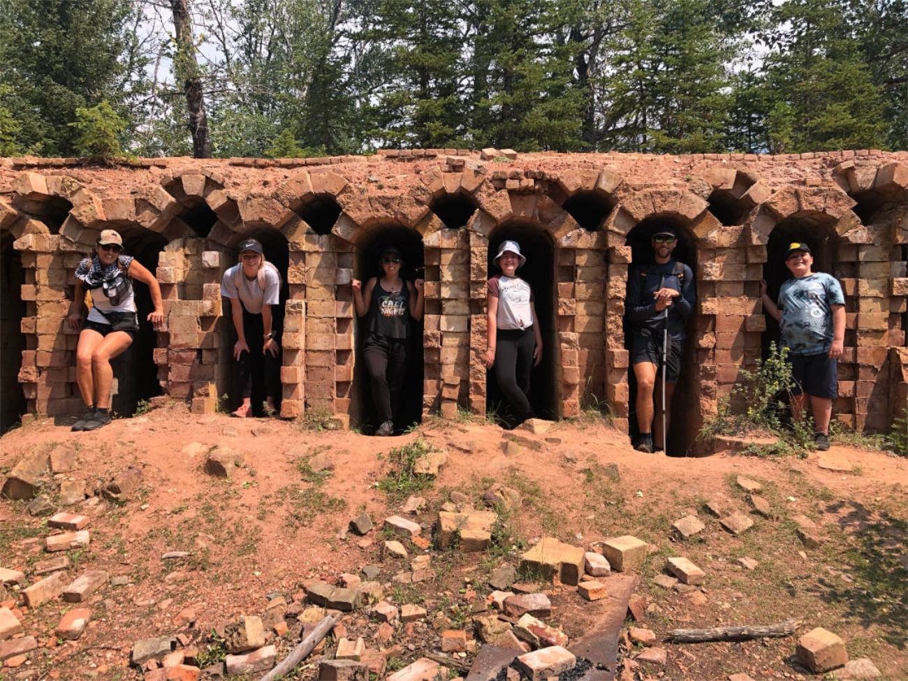 Hikers standing in arched brick ruins surrounded by trees.