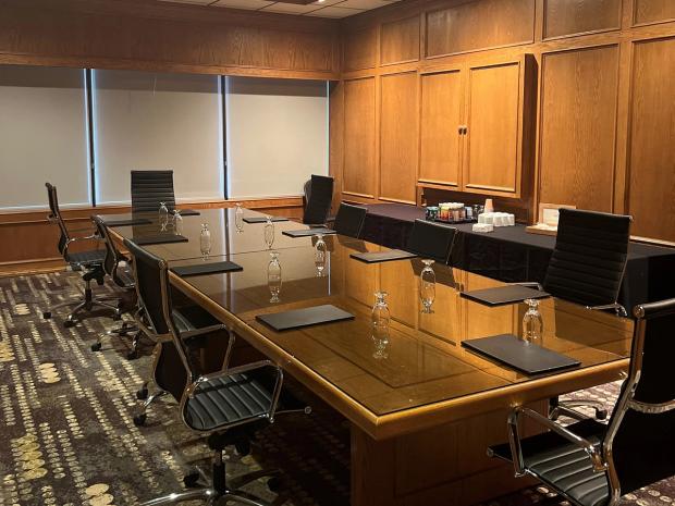 A boardroom table with water glasses and refreshments in the background.