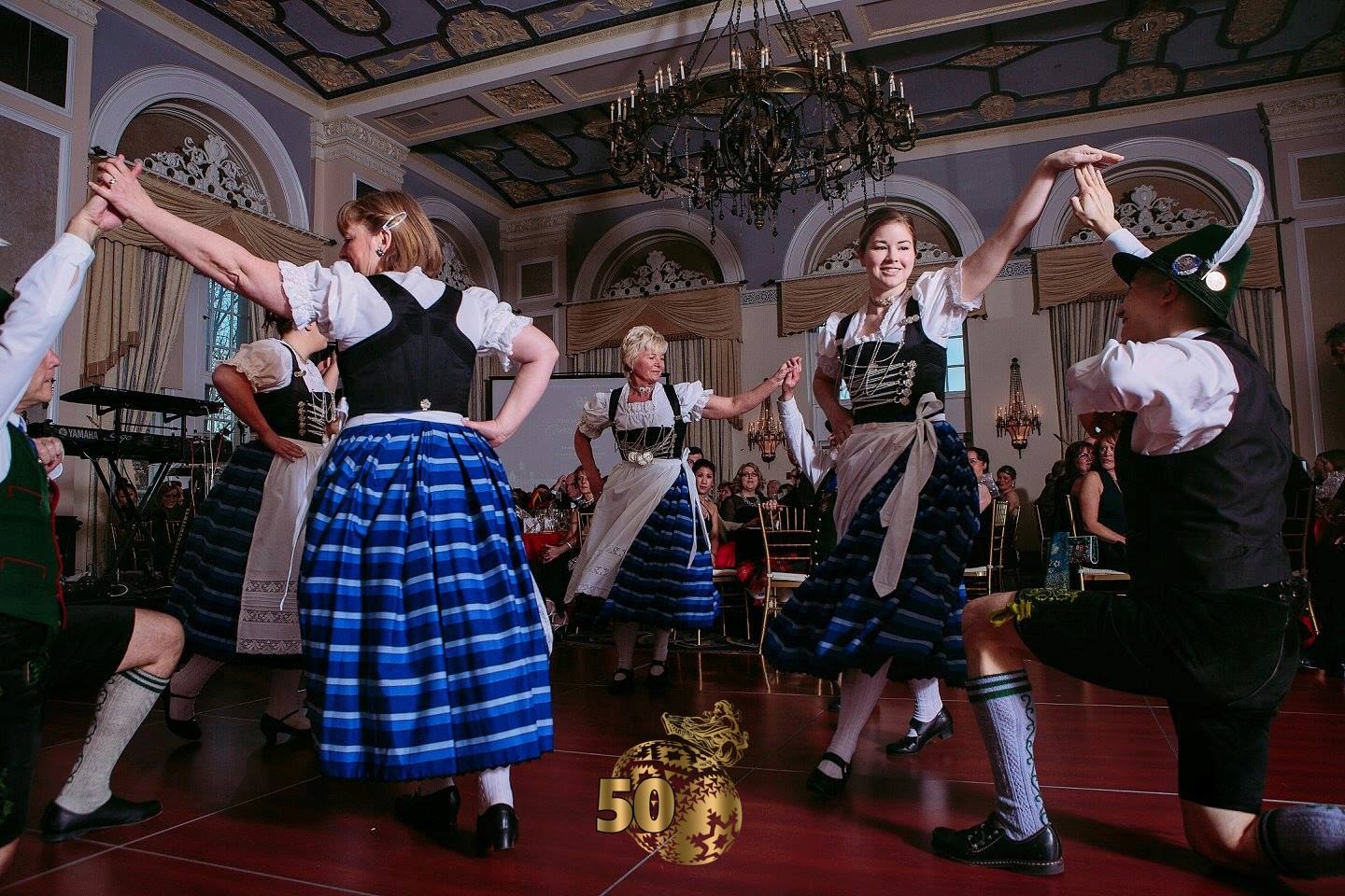 Dancers in traditional attire performing in a decorated hall with chandeliers.