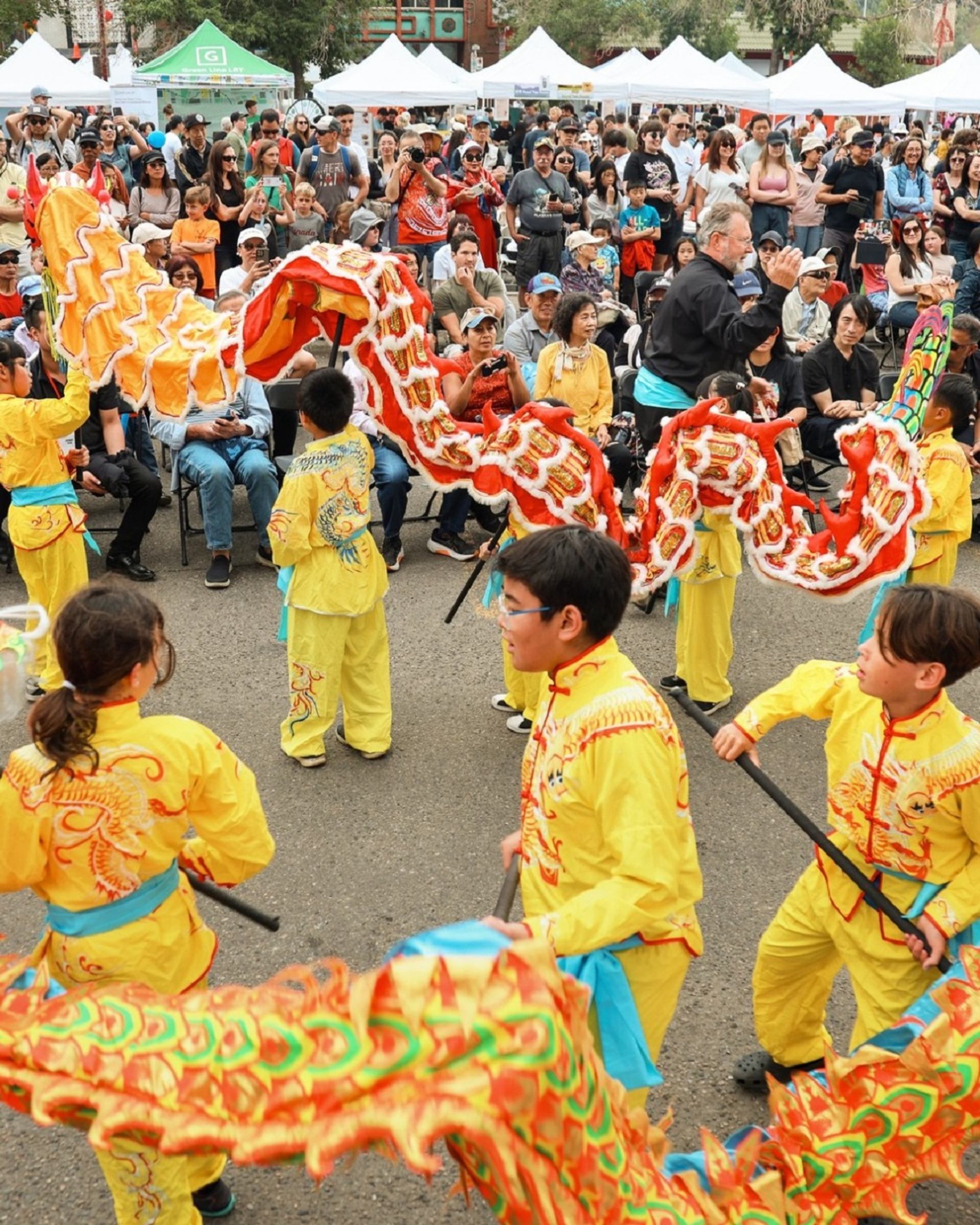 Performers in yellow outfits dancing with colorful dragon.