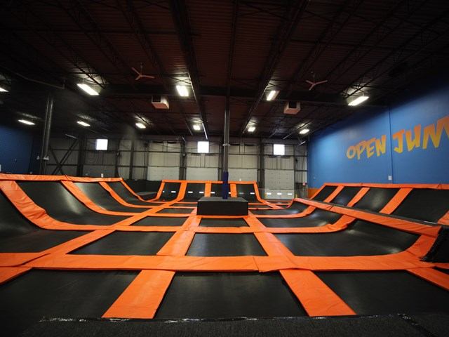 Indoor trampoline park with orange and black jumping lanes and wall sign reading "OPEN JUMP".