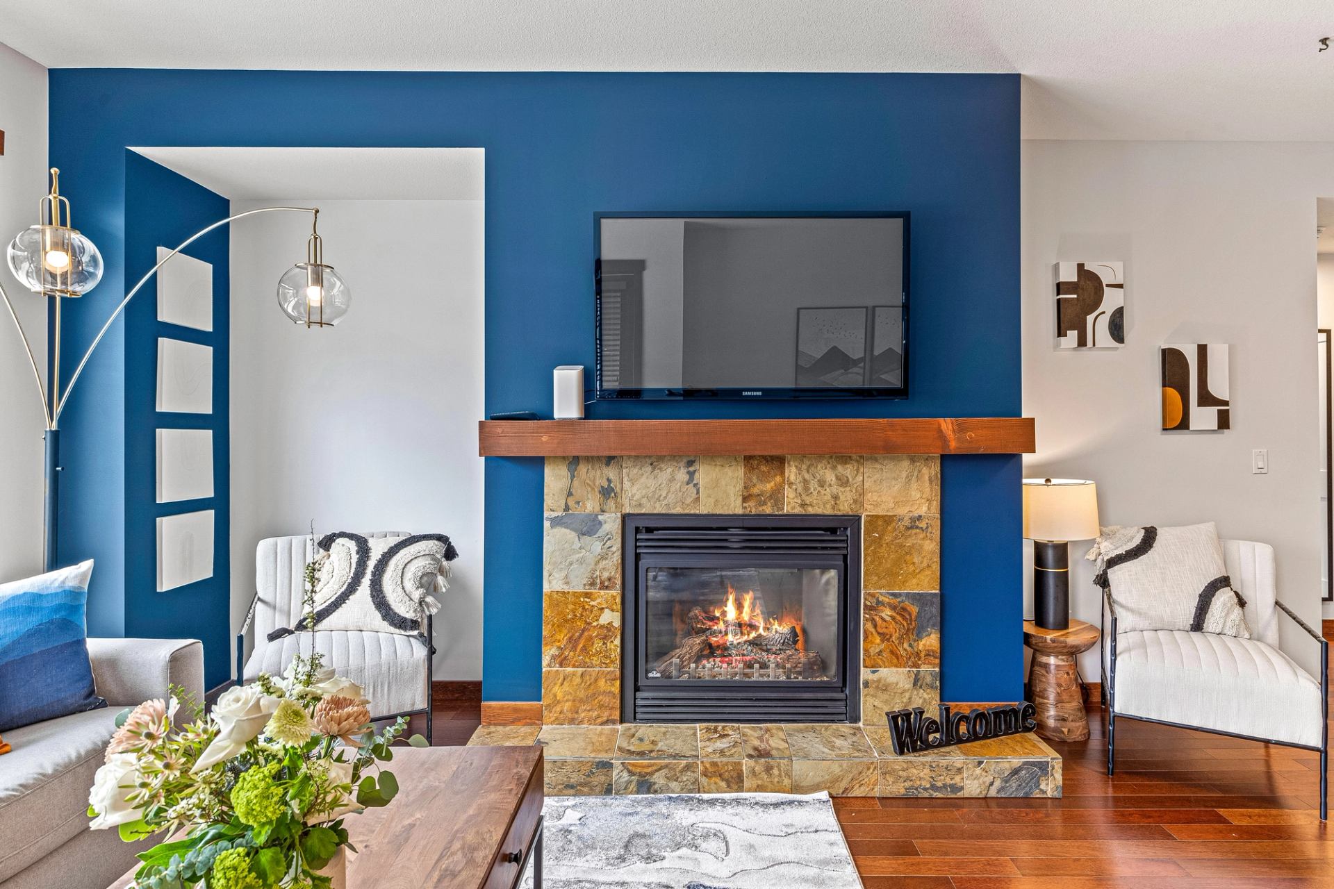 Living room with stone fireplace, blue accent wall, TV, and modern seating.
