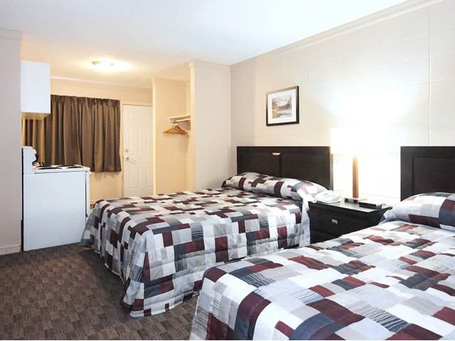 Motel room with two beds, kitchenette, and cozy decor.