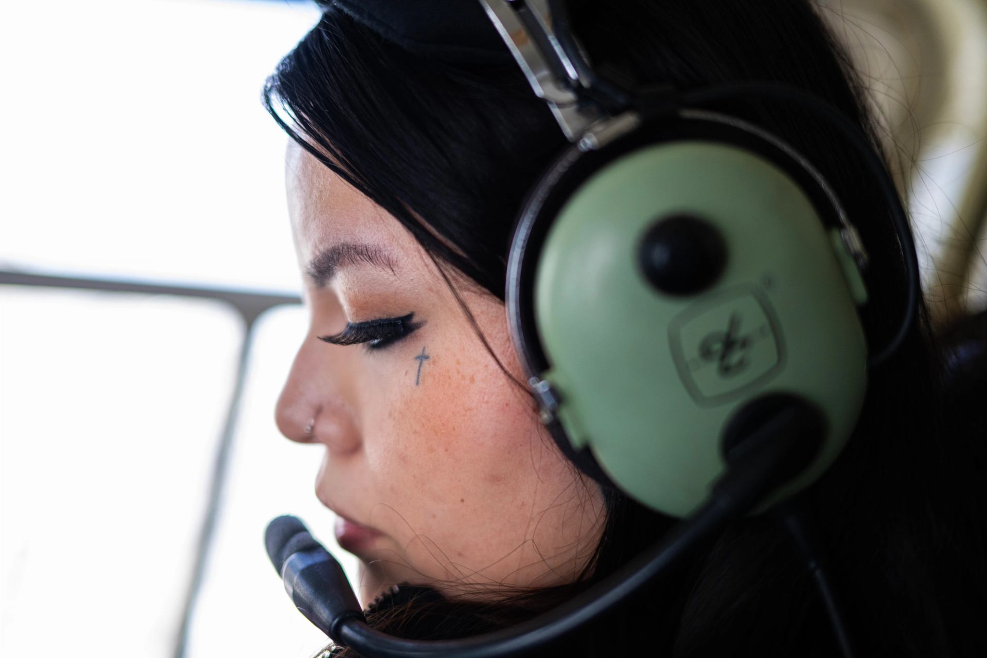 Close-up of person wearing green aviation headset inside aircraft.