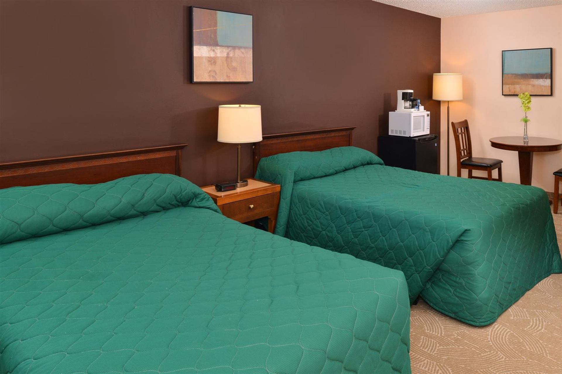 Guest room includes two beds, bedside lighting, a table, microwave, and compact refrigerator.