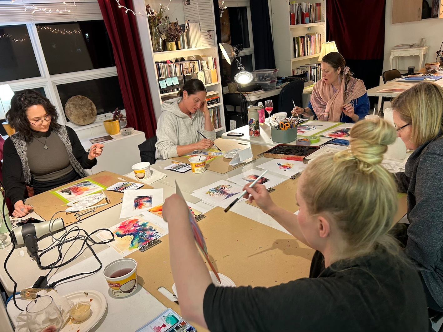A group of people painting with art supplies and snacks.