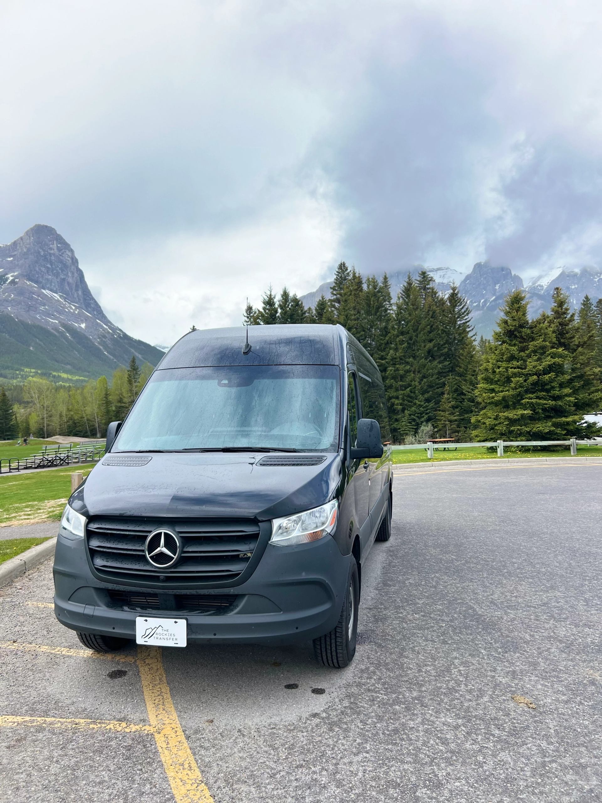 Mercedes van parked in scenic lot with mountains and trees in the background.