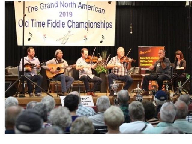 Musicians play fiddles and guitars onstage at Grand North American Fiddle Championships.