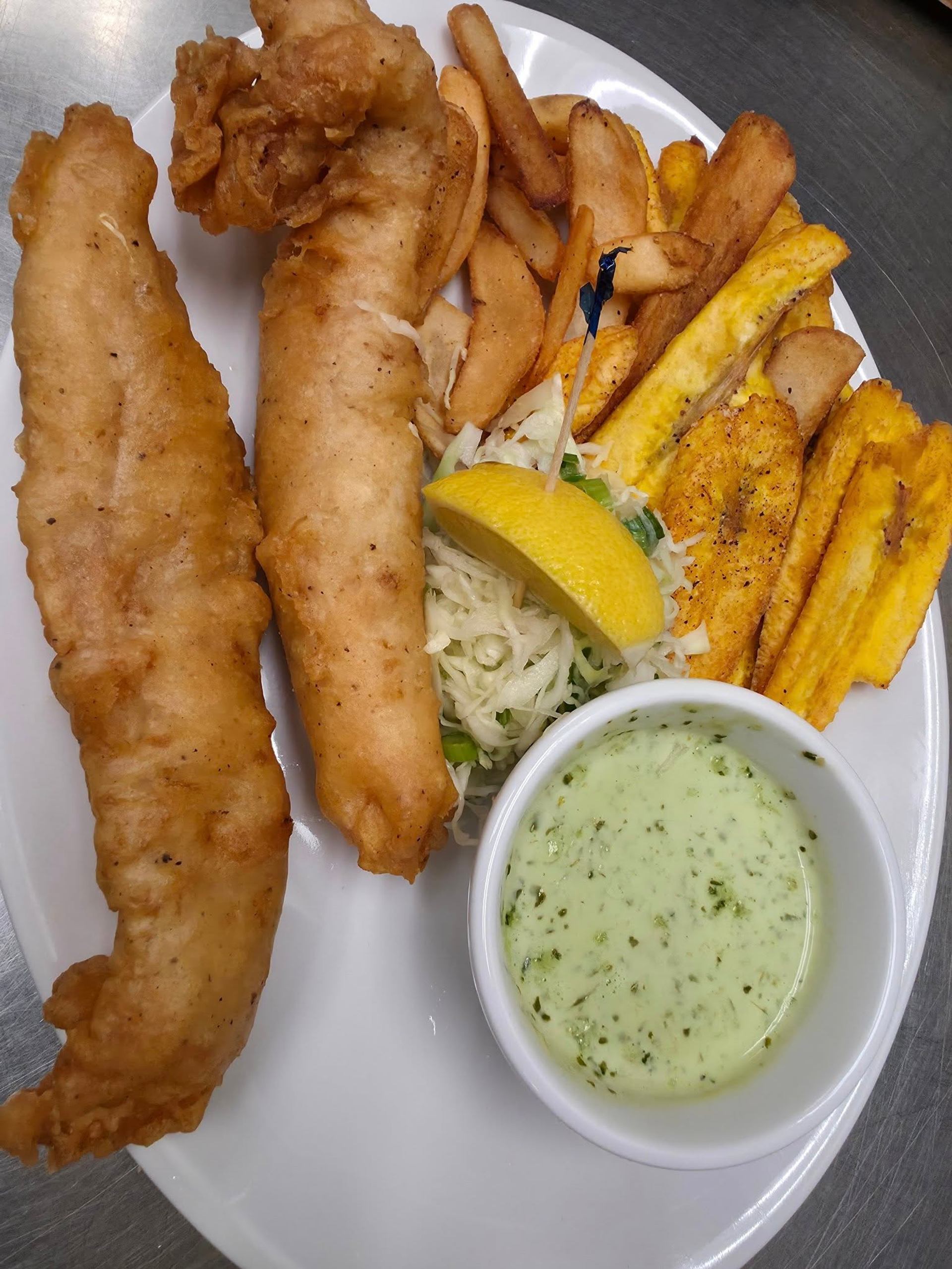 Fried fish fillets with fries, slaw, lemon, and dipping sauce