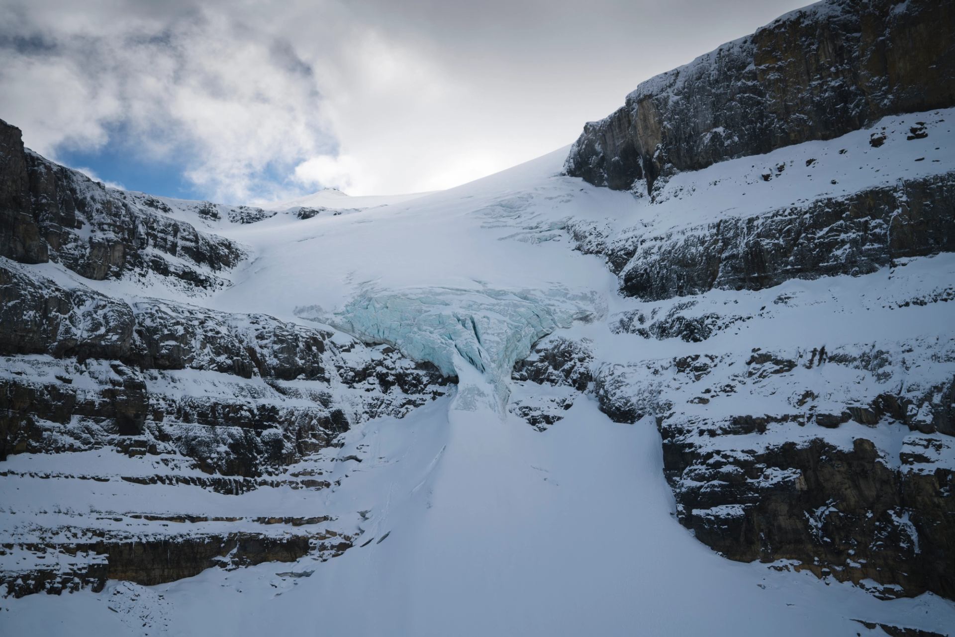 Massive glacier ice spilling between rocky cliffs in the Canadian Rockies.