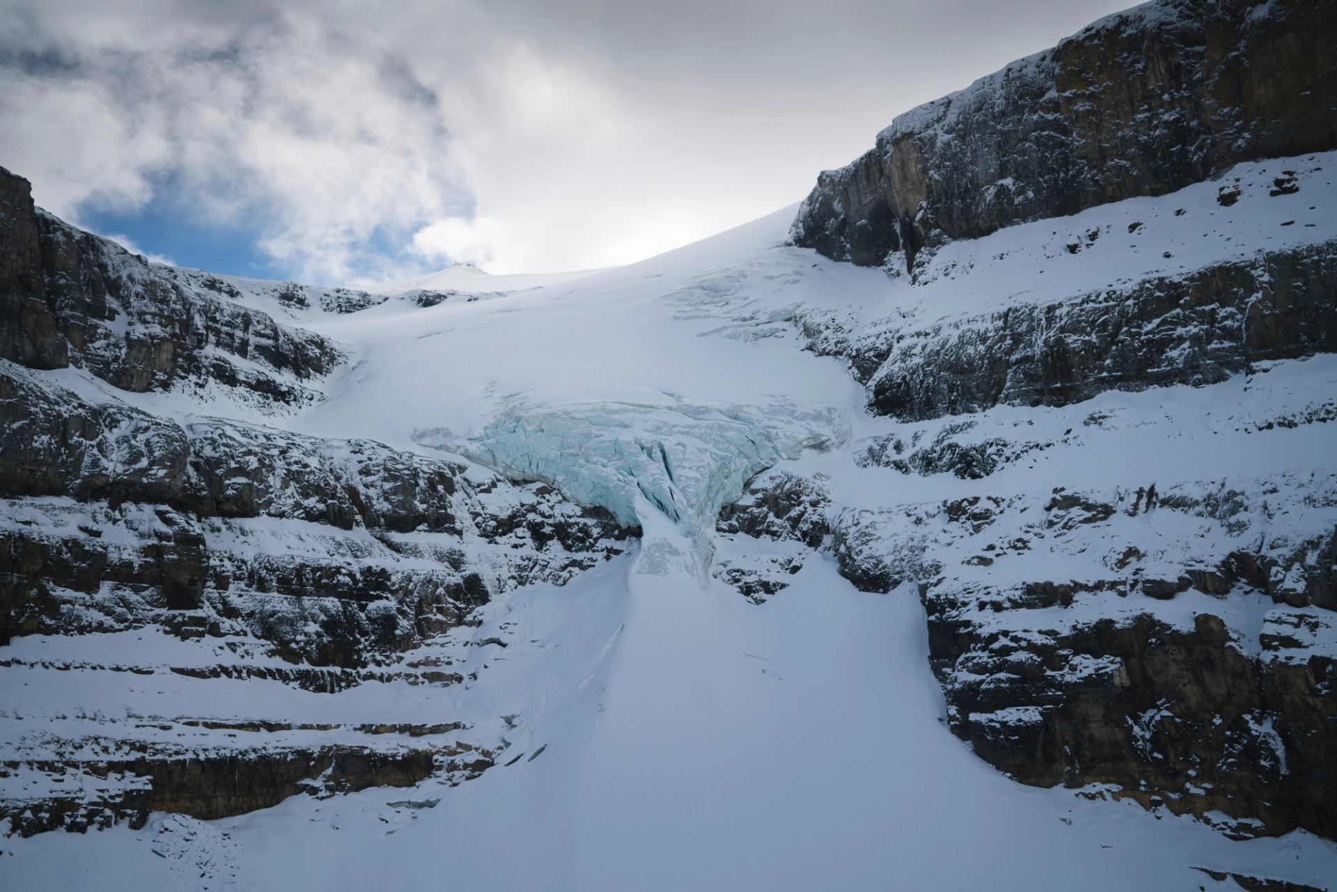 Massive glacier ice spilling between rocky cliffs in the Canadian Rockies.