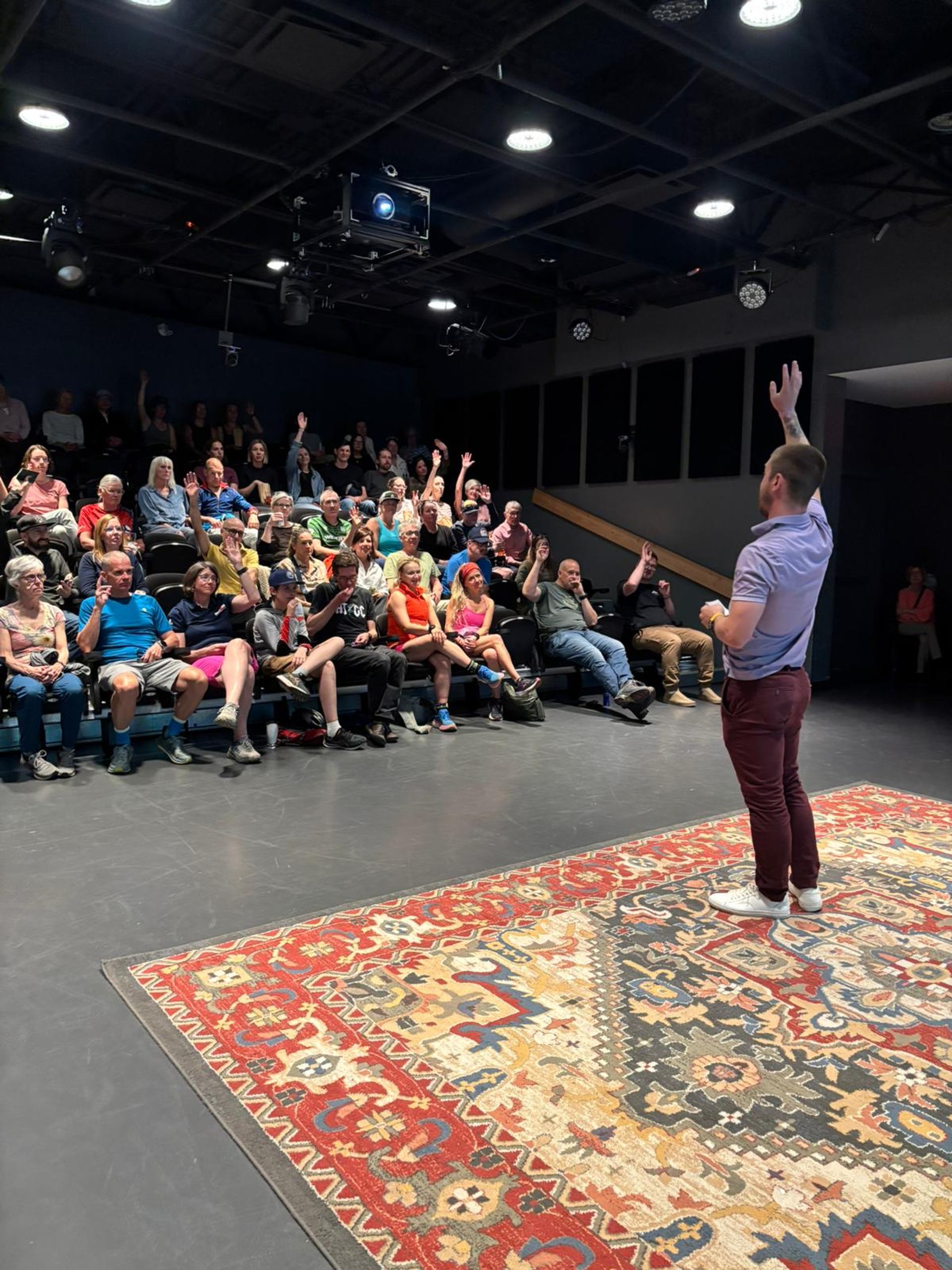 A speaker raises a hand as an audience responds during a film festival talk.