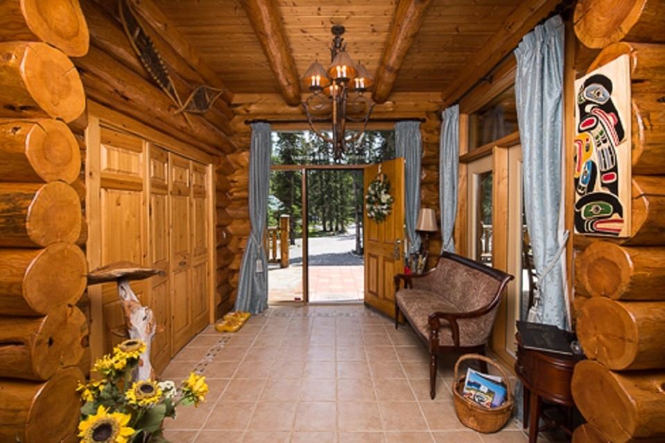 Rustic log cabin entry with wood furniture and scenic outdoor view.